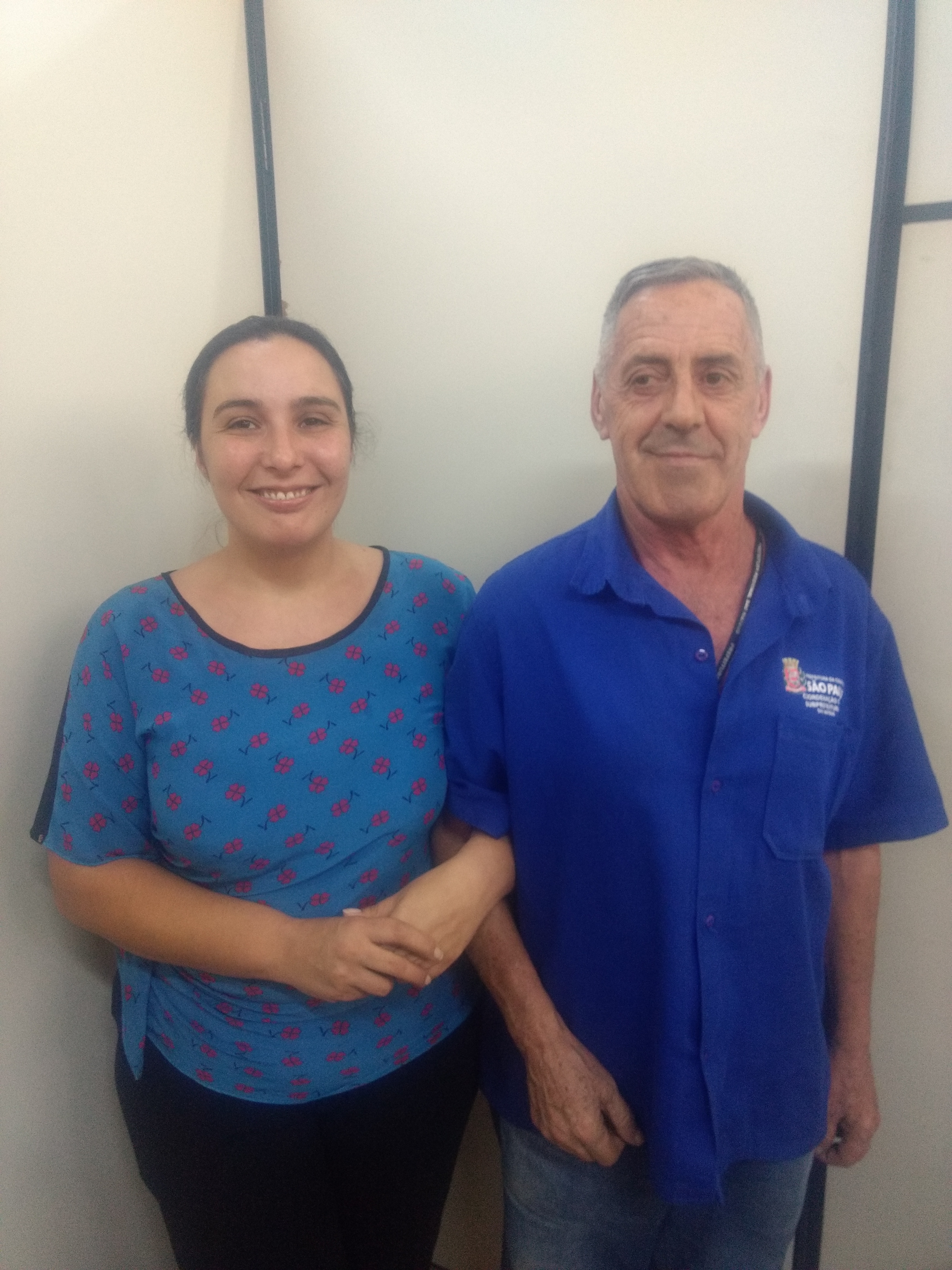 Gloria, à esquerda, Oscar à direita, ambos de camisa azul, com os braços entrelaçados.